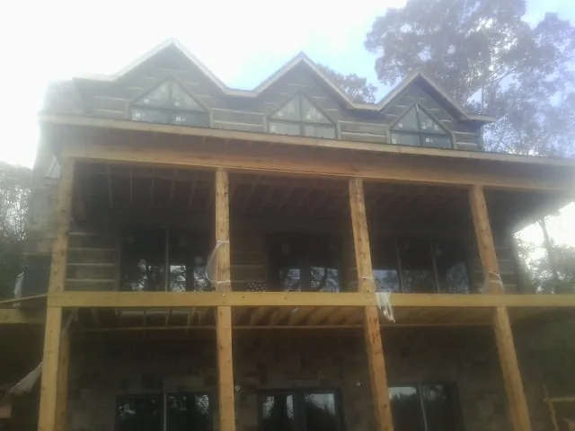 Dormers and porch framing on a large log home under construction — Roof Coating work by our crew in Patterson